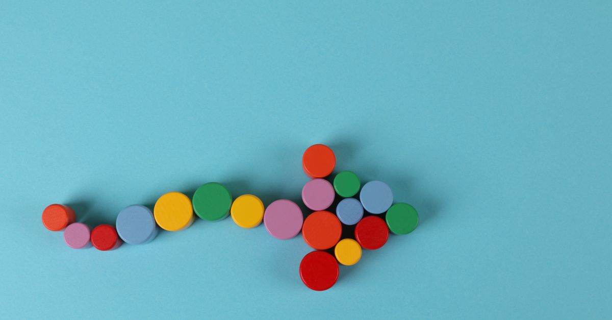 A vibrant arrow composed of colorful cylinders against a minimalist blue backdrop.